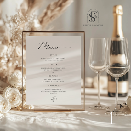 Menu de table mariage personnalisé présenté dans un cadre doré sur une table de réception