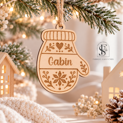 Suspension de Noël personnalisée en bois en forme de moufle avec le prénom Gabin gravé, décorée d'un flocon de neige, d'un cœur et de motifs végétaux, suspendue à un sapin de Noël.